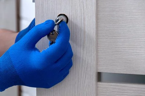 The guy is installing a new door lock in the room. Repair in the house. A guy Stock Photos