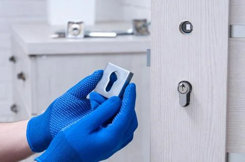 The guy is installing a new door lock in the room. Repair in the house. A guy Stock Photos