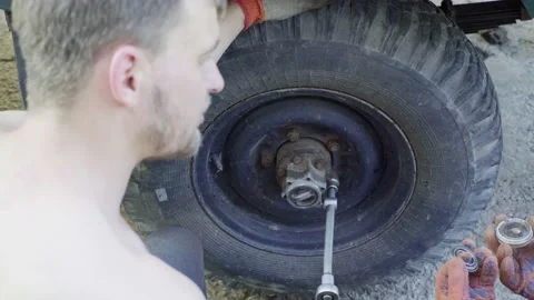 Guy installs a wheel on an old car, close-up, tightens the bolts Stock Footage 144616512