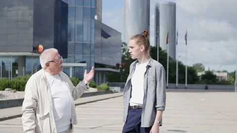 Guy interviews pensioner against multistory office building Stock Footage 147171887