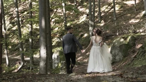 Guy in jacket and black pants walks by handle with girl in white lush long dress Vidéo 140276197