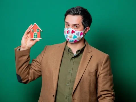 Guy in jacket and face mask hold toy house Stock Photos