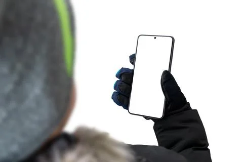 Guy in a jacket with a cap and gloves is holding a mobile phone. The backgrou Stock Photos