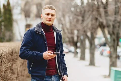 Guy in jacket simple stands with phone Stock Photos