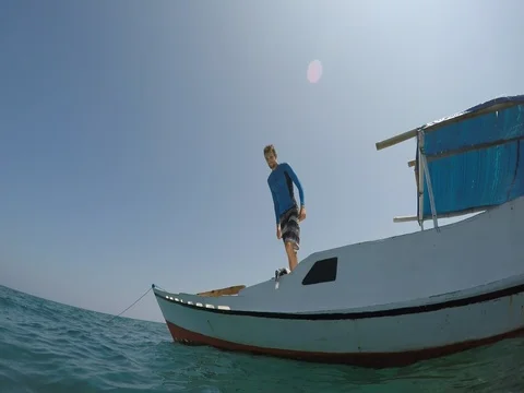 Guy jumping off boat into turquoise water Stock Footage 80209423