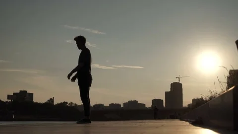 A guy jumping in the street against the backdrop of the city at sunset 库存影片 81692502