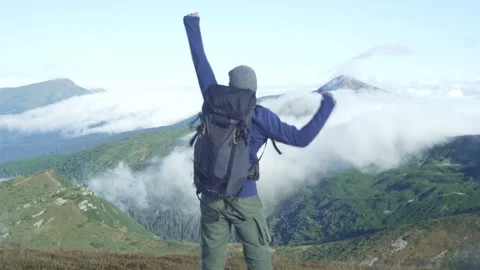 The guy jumps and raises his hands to the top conquering the top of the mountain Stock Footage 218438866