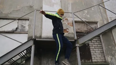The guy jumps down a metal ladder at the side of the building. Stock Footage 151689387