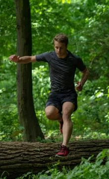 The guy jumps over a large log while participating in an ocr race Stock Photos