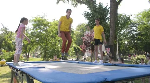 The guy jumps on a trampoline across the rope in the park Stock Footage 50559522