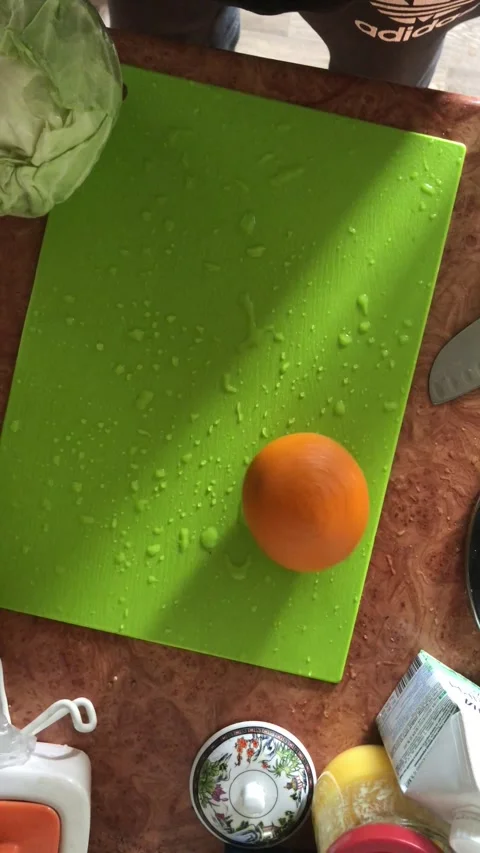 A guy in the kitchen on a board of bright sweet color twists an orange Stock Footage 241180236