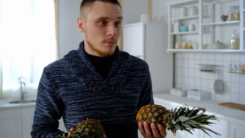 Guy in the kitchen holds pineapples Stock-Footage 127263682