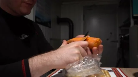 A guy with a knife in his hands is peeling carrots Video stock 232974776