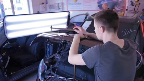 The guy knocks with a hammer on the car to align the dent on technology PDR Stock Footage 113101174