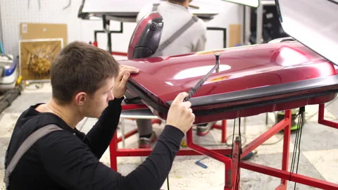 The guy knocks with a hammer on the car to align the dent on technology PDR. Stock Footage 152499440