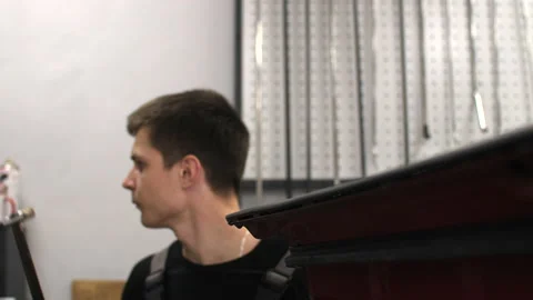 The guy knocks with a hammer on the car to align the dent on technology PDR. Stock Footage 152499450