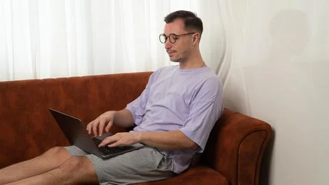 A guy with a laptop on the couch, remote work and study Stock Photos