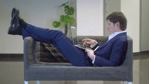 Guy laying in couch computing on pc Stock Footage 73458514