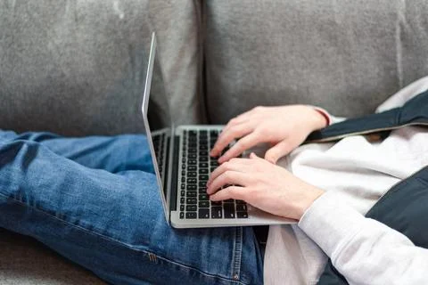 Guy laying on couch using laptop Stock Photos