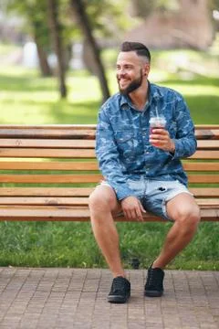 A guy with lemonade is resting in a park on a bench in the spring. Sunny day. 스톡 사진