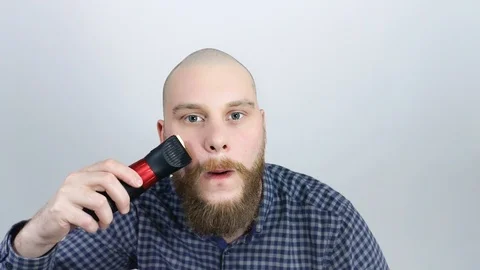 The guy leveled his beard looking in the reflection of his bald head. Stock Footage 122012564