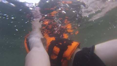 Guy in a life jacket is swimming under water Stock Footage 99804048