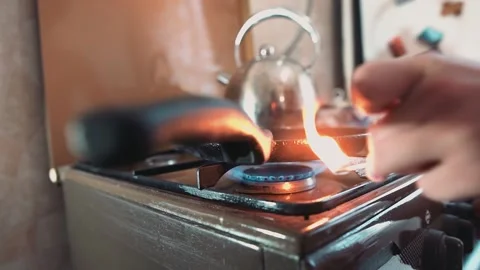 The guy lights the gas under the pan on the stove in the kitchen Stock Footage 134424358