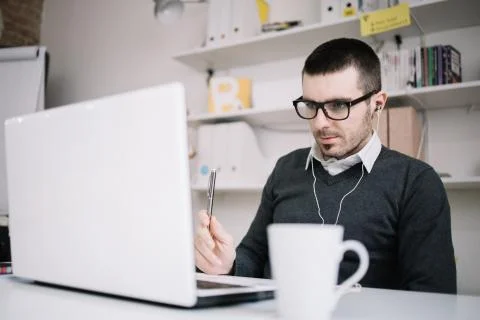 Guy listening music while working on laptop in office Stock Photos