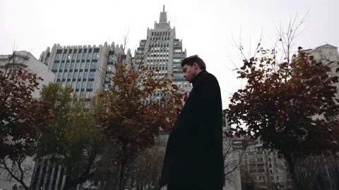 A guy in long black clothes is walking around a big city in autumn Stock Footage 157924569