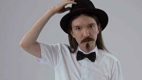 Guy with long hair puts on a false moustache and beard and poses for the camera. Stock Footage 287915622