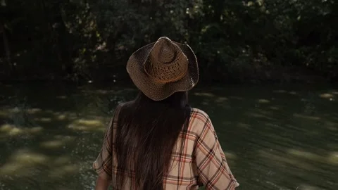 Guy with long hair sits by a river in a wooded area Stock Footage 264509800