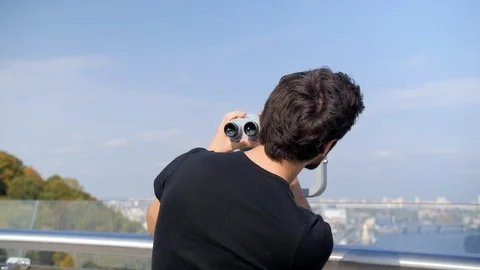 Guy look through binoculars at the city panorama Stock Footage 117433545