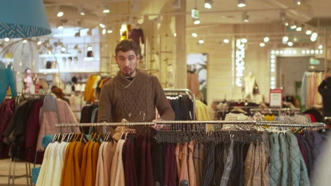 Guy is looking for a certain sweater in a store Stock Footage 119423444