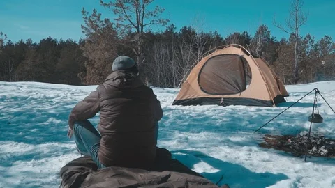 The guy is looking into the distance near the fire and tents Stock Footage 87586294