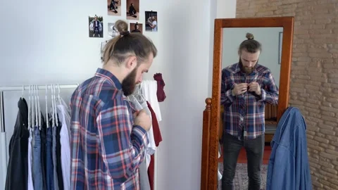 Guy is looking into the mirror buttoning the shirt Putting together an outfit Stock Footage 147893251