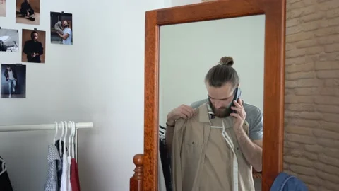 Guy is looking  mirror Putting together an outfit Talking Calling on phone Stock Footage 147893864