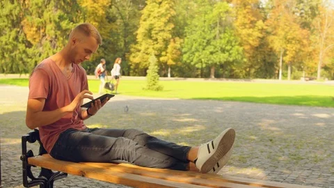 Guy looking photos on device outdoors Stock Footage 99860813