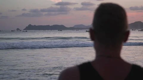 Guy looking at the sunset beach 動画素材 145298786