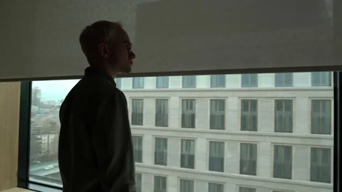 The guy looks out the window from the office Stock Footage 130499801