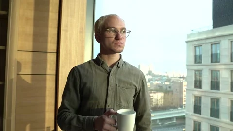 The guy looks out the window from the office Stock Footage 130499953