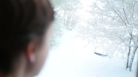 A guy looks out the window at the snowfall 库存影片 68771216