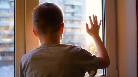 The guy looks out the window at the sun. Plays a hand with sunlight 库存影片 73547209