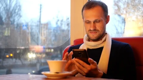 Guy looks into the phone and drinks coffee 動画素材 102545650