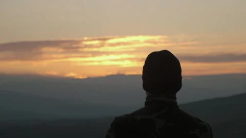 The guy looks at the sunset in the mountains Stock Footage 171636739