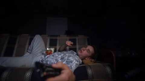 The guy is lying watching TV and eating popcorn Stock Footage 126093342