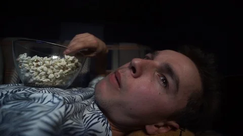 The guy is lying watching TV and eating popcorn.Close up Stock Footage 126093398