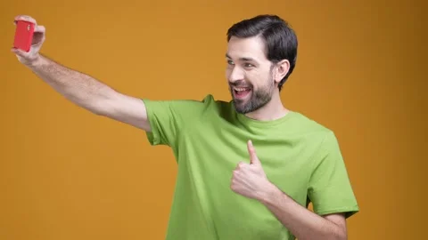 Guy make selfie on gadget with thumb up symbol isolated shine color background Video stock 204990419