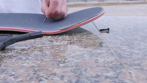 Guy makes bolt holes in the skateboard Video stock 80557368