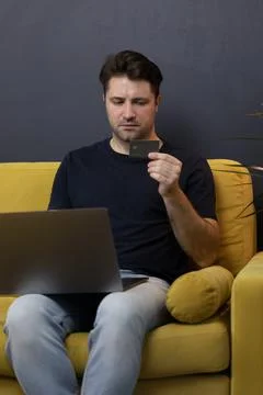 Guy makes purchases or payments online, looks at credit card cvv security code Stock Photos