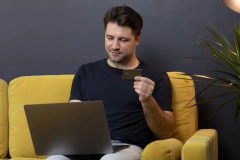 Guy makes purchases or payments online, looks at credit card cvv security code 스톡 사진